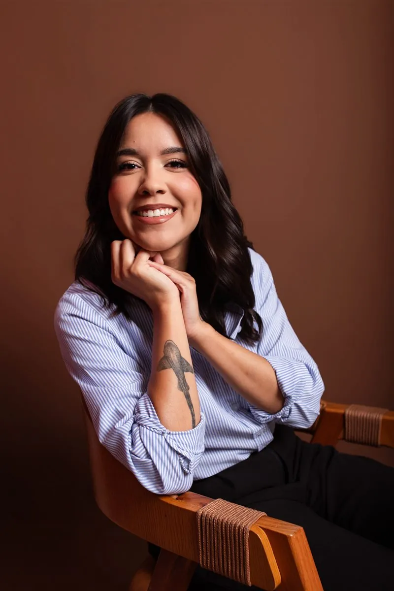Luiza Mamede sorrindo, com as mãos apoiadas no queixo